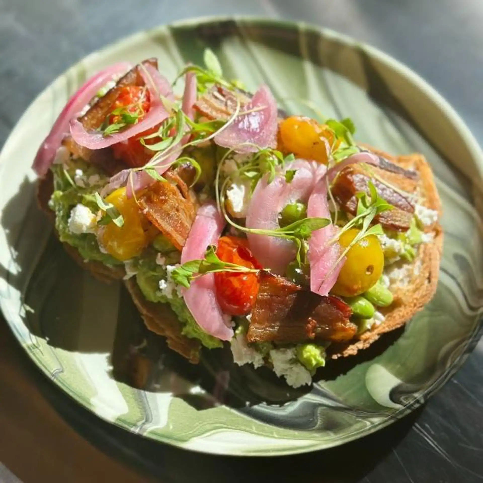 Avocado toast with bacon, cherry tomatoes and pickled onions at Hash House