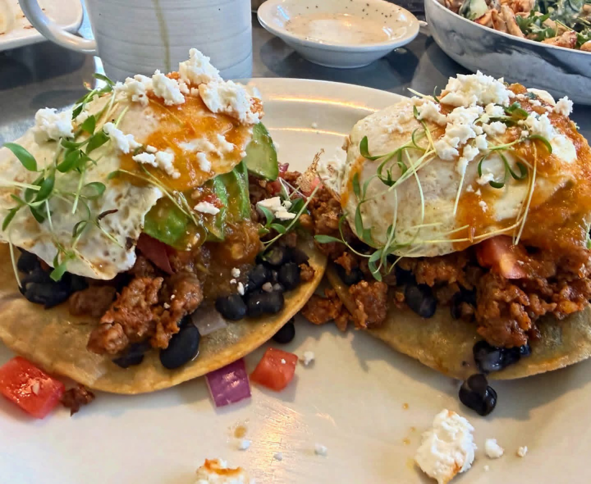 Tostadas topped with fried eggs, black beans, crumbled meat and feta at Hash House