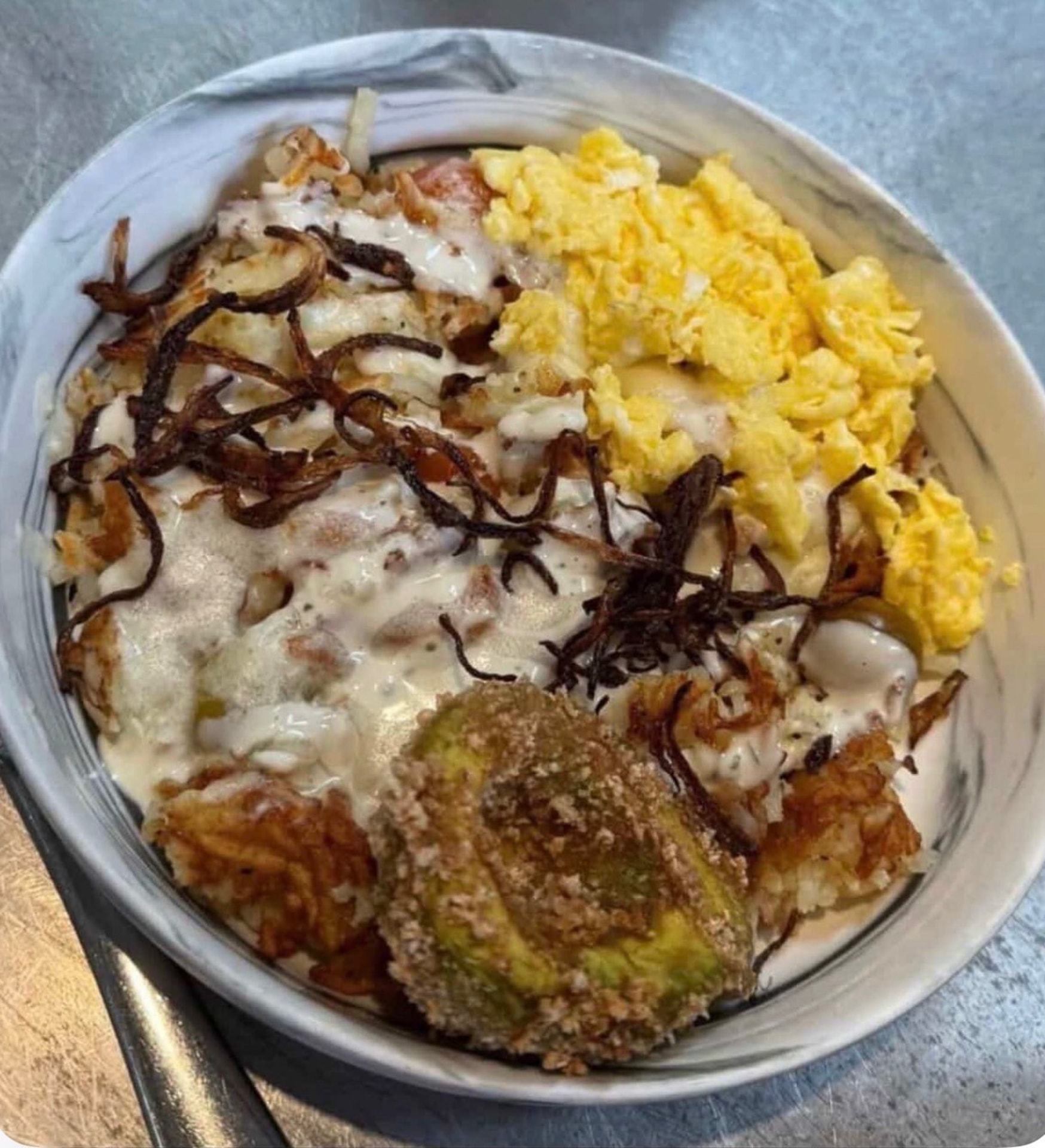 Bowl with scrambled eggs, crispy fried avocado, potatoes and crispy onions at Hash House
