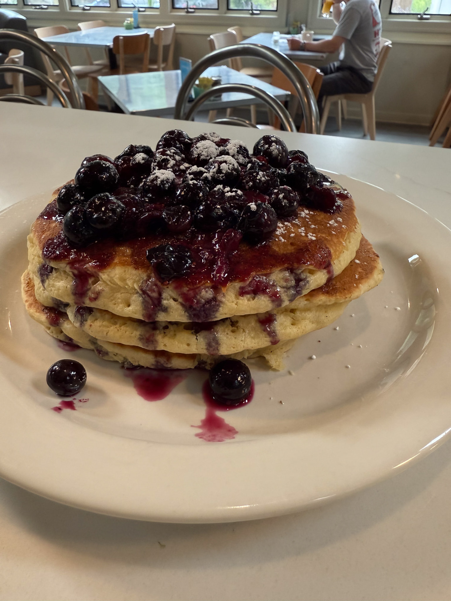 Stack of pancakes topped with warm blueberries and powdered sugar at Hash House