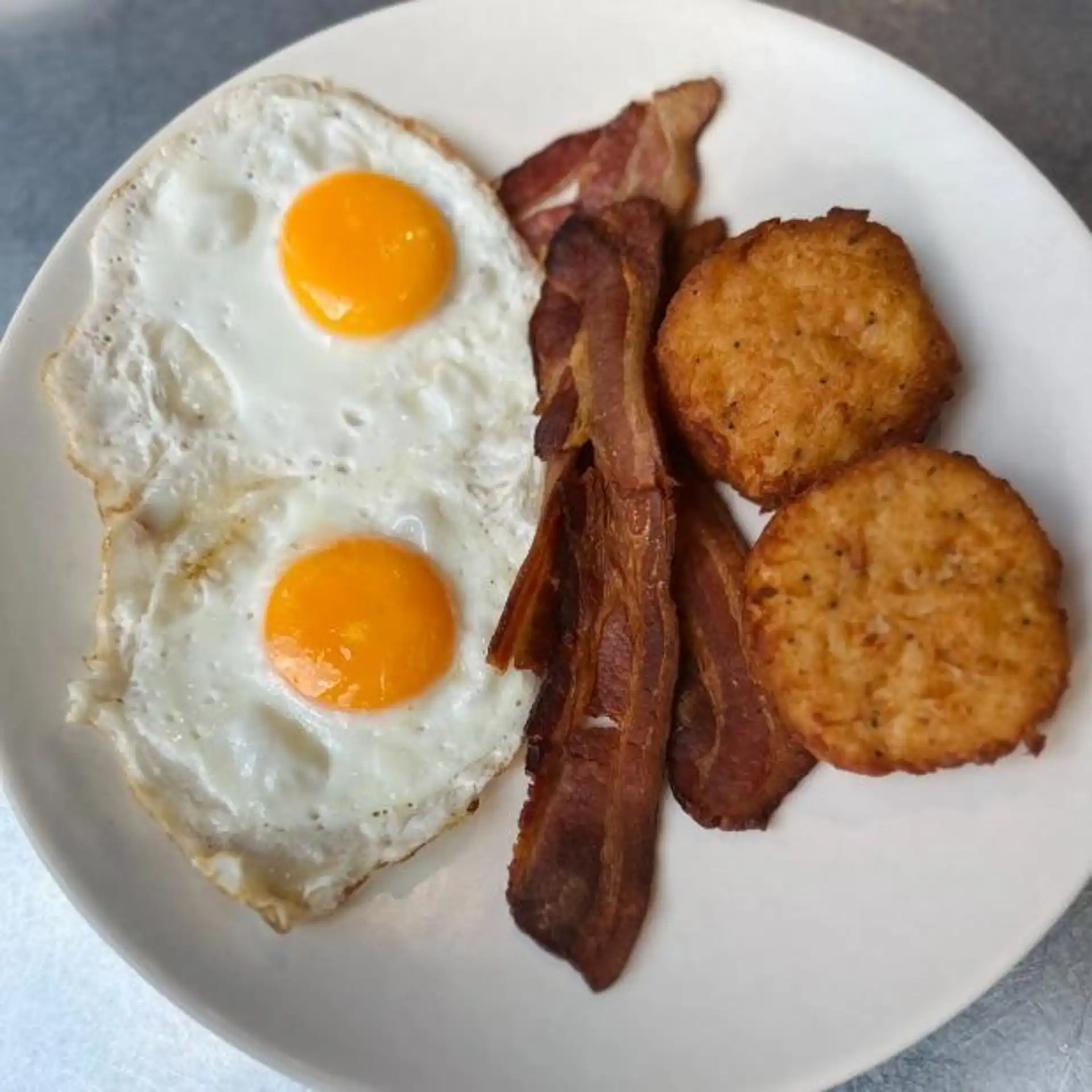 Fried eggs with bacon and hash browns at Hash House