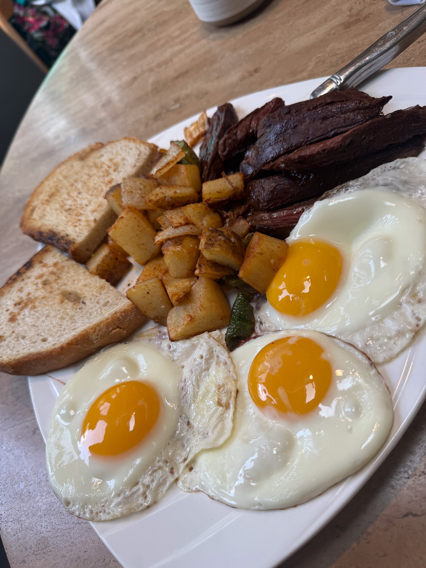 Steak with three sunny-side eggs, breakfast potatoes and toast at Hash House
